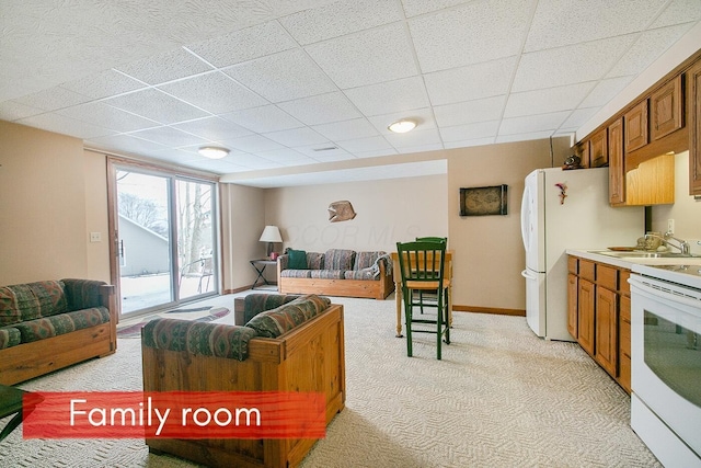 living room with a paneled ceiling, sink, and light carpet