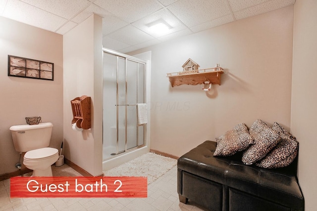 bathroom featuring a drop ceiling, toilet, and walk in shower