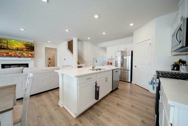 kitchen featuring backsplash, sink, white cabinetry, an island with sink, and stainless steel appliances