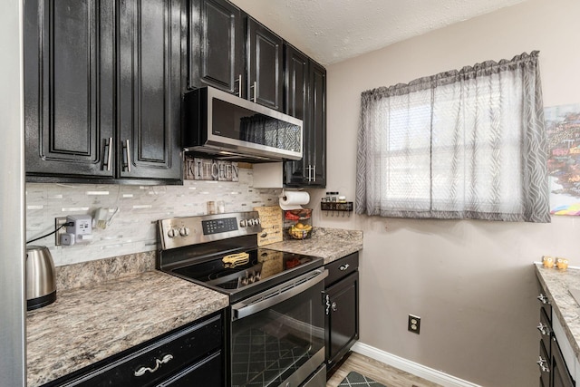 kitchen with stainless steel appliances, tasteful backsplash, light stone countertops, a textured ceiling, and light hardwood / wood-style flooring