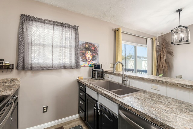 kitchen featuring hardwood / wood-style flooring, appliances with stainless steel finishes, decorative light fixtures, a textured ceiling, and sink