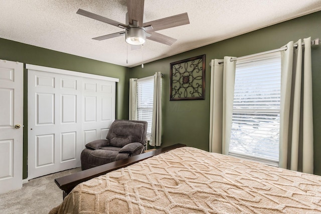 bedroom with ceiling fan, light colored carpet, a textured ceiling, and a closet