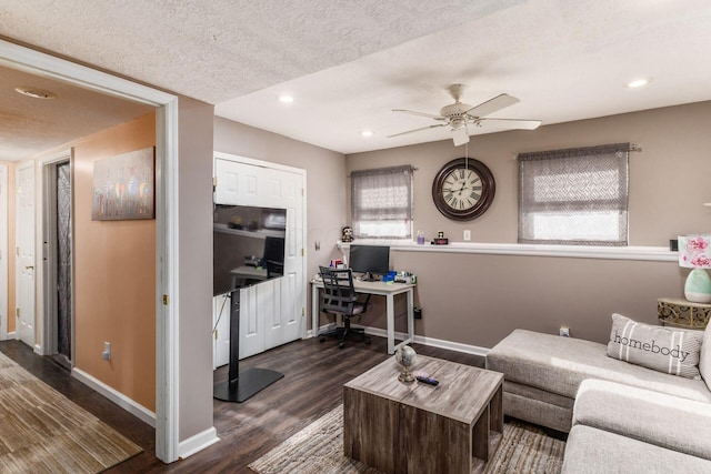 living room featuring ceiling fan, dark wood-type flooring, and a textured ceiling