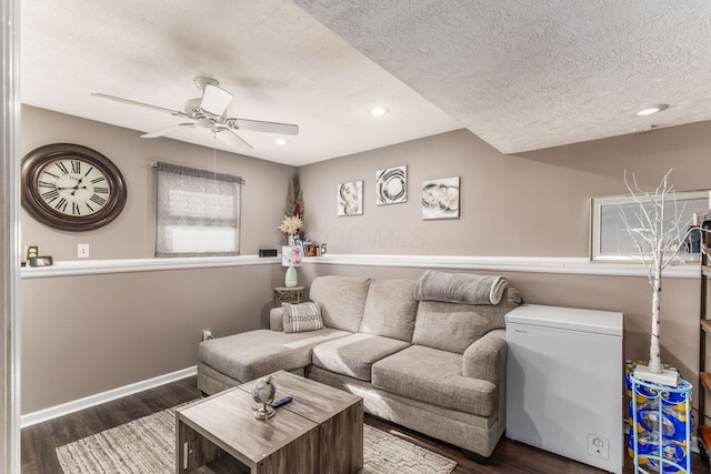 living room featuring a textured ceiling, ceiling fan, and dark hardwood / wood-style flooring