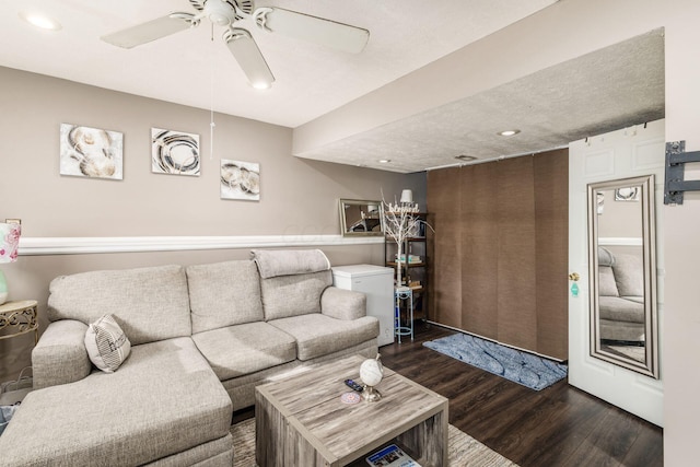 living room featuring ceiling fan and dark hardwood / wood-style flooring