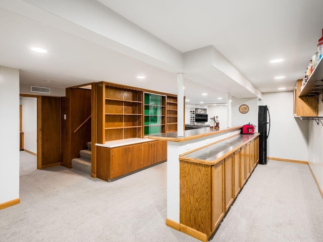 kitchen with black refrigerator, kitchen peninsula, and light carpet