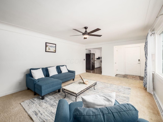 carpeted living room with crown molding, ceiling fan, and a baseboard heating unit