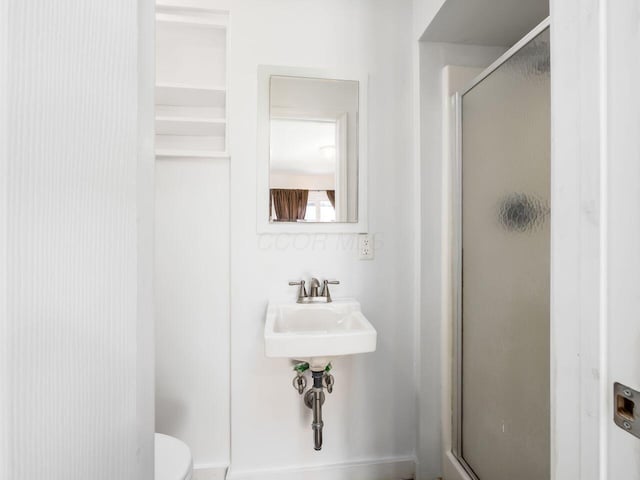 bathroom with sink, toilet, and a shower with door