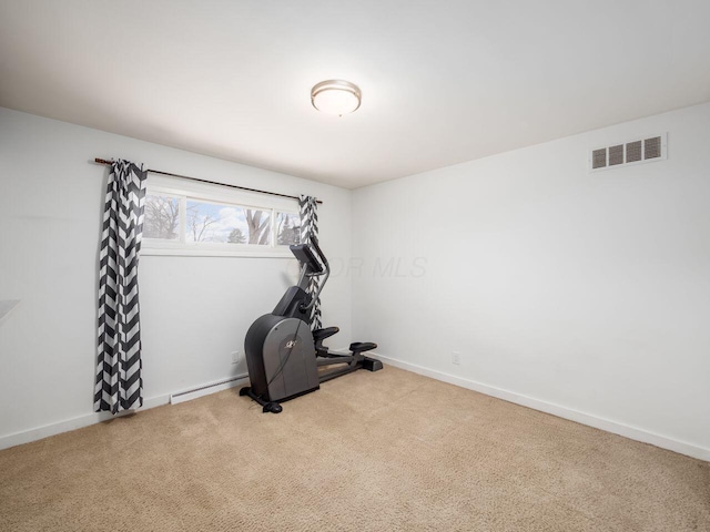 exercise room featuring light carpet and a baseboard heating unit