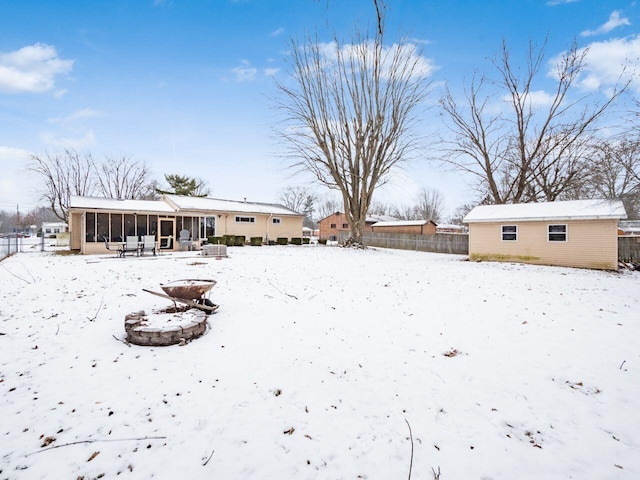 yard covered in snow featuring an outdoor structure and a sunroom