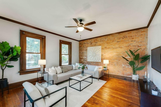 living room featuring wood-type flooring, brick wall, crown molding, and ceiling fan