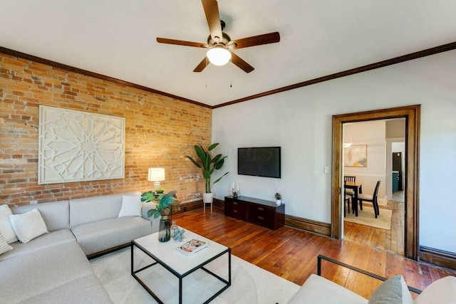 living room with ceiling fan, wood-type flooring, brick wall, and ornamental molding