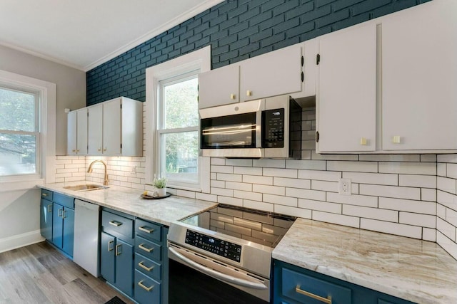 kitchen with blue cabinetry, stainless steel appliances, and white cabinetry