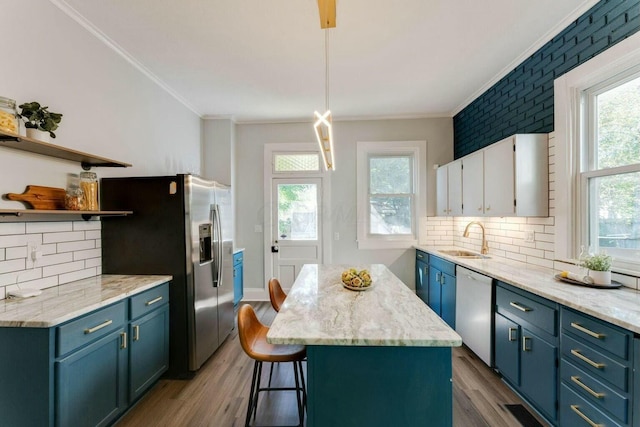 kitchen featuring pendant lighting, decorative backsplash, sink, crown molding, and stainless steel appliances