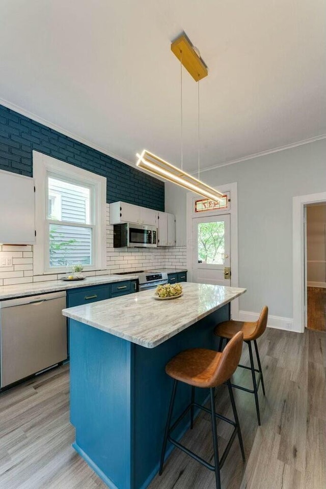 kitchen with light hardwood / wood-style floors, a center island, stainless steel appliances, and pendant lighting