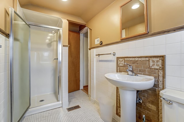 bathroom with tile patterned floors, toilet, an enclosed shower, sink, and tile walls