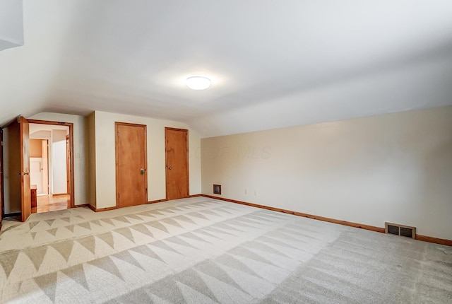 bonus room with vaulted ceiling and light colored carpet