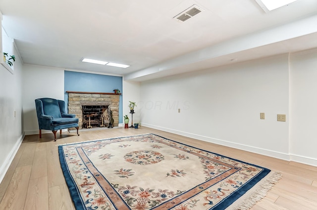 sitting room with hardwood / wood-style flooring and a stone fireplace