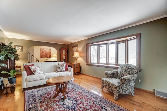 living room with ornamental molding and light hardwood / wood-style floors