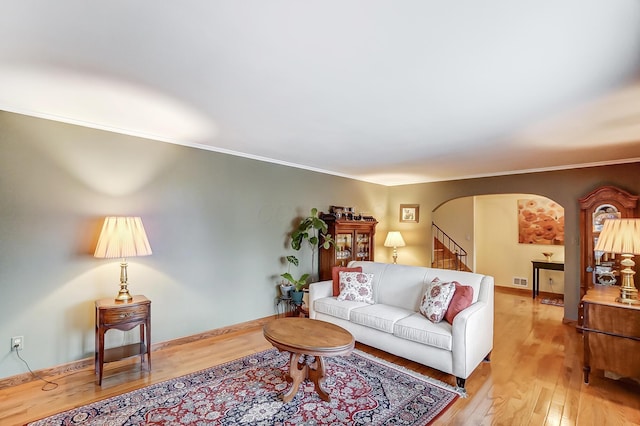 living room with ornamental molding and light hardwood / wood-style floors