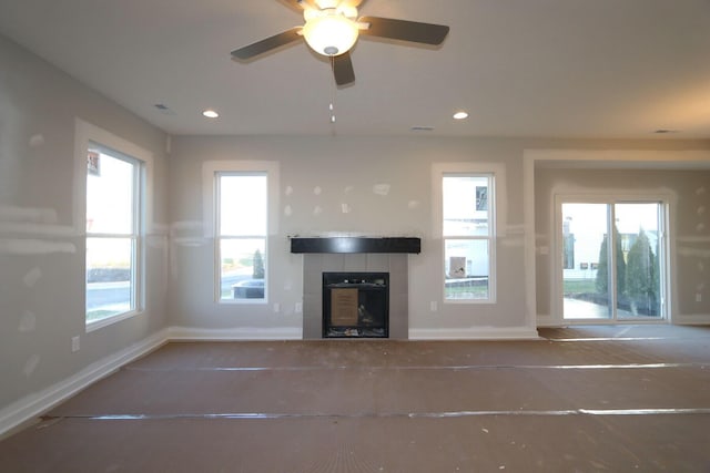 unfurnished living room featuring ceiling fan, a fireplace, and plenty of natural light