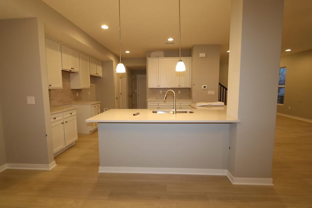 kitchen with white cabinetry, decorative backsplash, sink, hanging light fixtures, and a center island