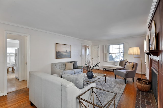 living room with crown molding, hardwood / wood-style flooring, and a brick fireplace