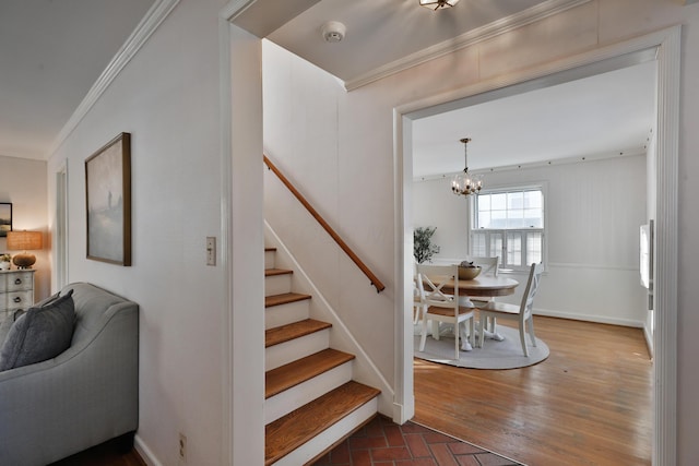 staircase with crown molding and a chandelier