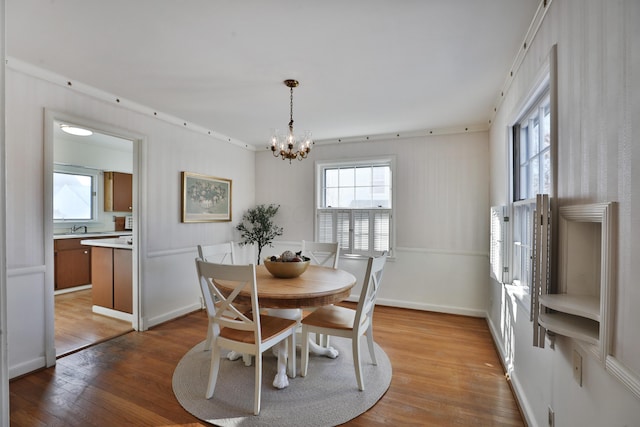 dining room with crown molding, light hardwood / wood-style floors, sink, and a notable chandelier