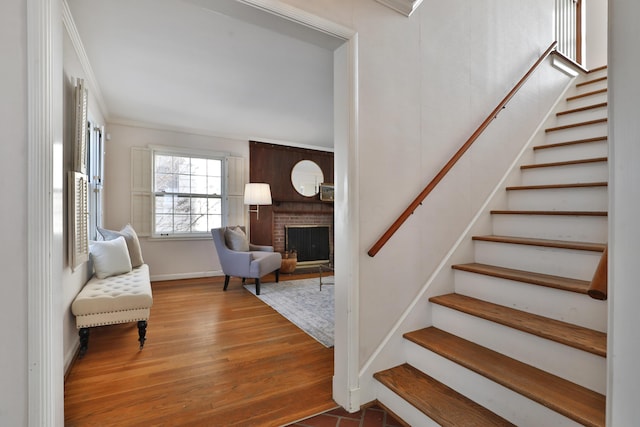 staircase with a fireplace, hardwood / wood-style floors, and ornamental molding