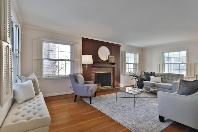 living room featuring wood-type flooring, ornamental molding, and a fireplace