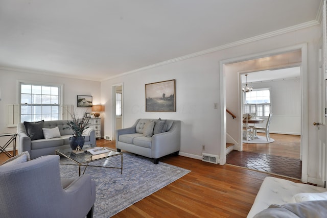 living room featuring a notable chandelier, ornamental molding, and dark wood-type flooring