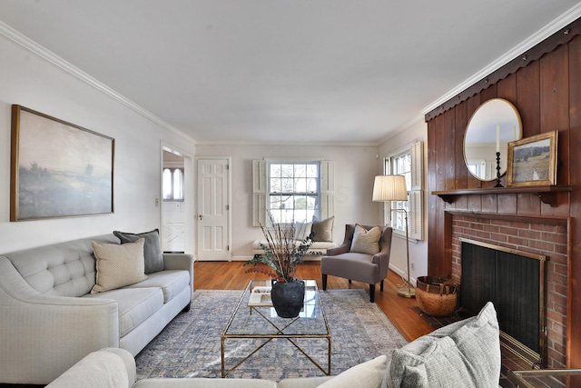 living room with crown molding, wood-type flooring, and a brick fireplace