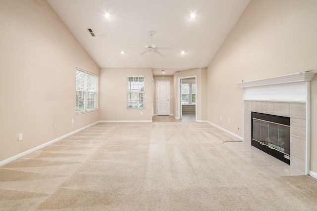 unfurnished living room with ceiling fan, light colored carpet, a tile fireplace, and plenty of natural light