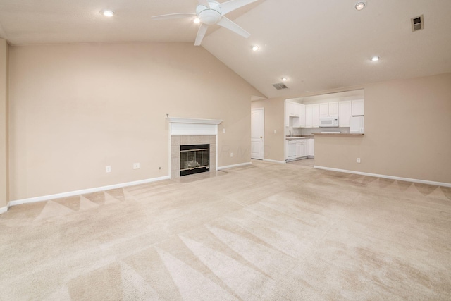 unfurnished living room featuring light carpet, beamed ceiling, high vaulted ceiling, ceiling fan, and a tiled fireplace