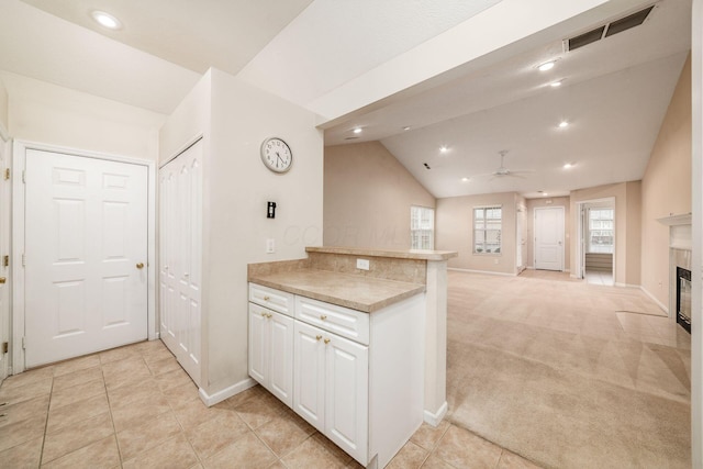 kitchen with white cabinetry, kitchen peninsula, ceiling fan, lofted ceiling, and light colored carpet