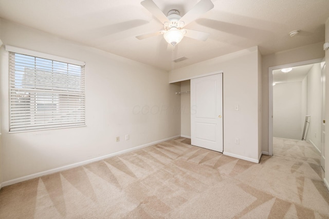 unfurnished bedroom featuring ceiling fan, a closet, and light carpet