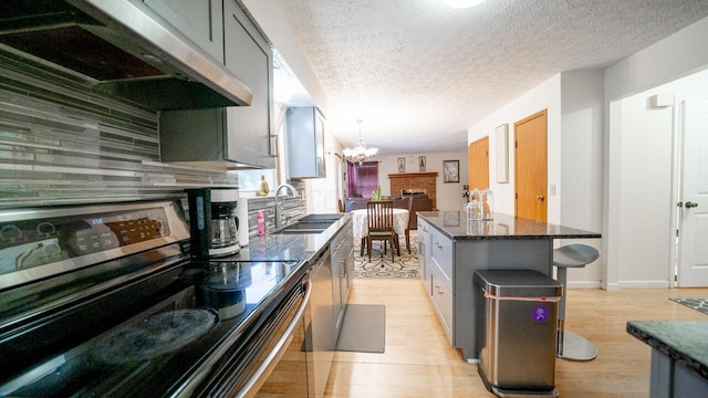 kitchen featuring a breakfast bar, sink, stainless steel range with electric cooktop, ventilation hood, and a kitchen island