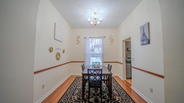 dining space with a chandelier, a textured ceiling, and light hardwood / wood-style flooring