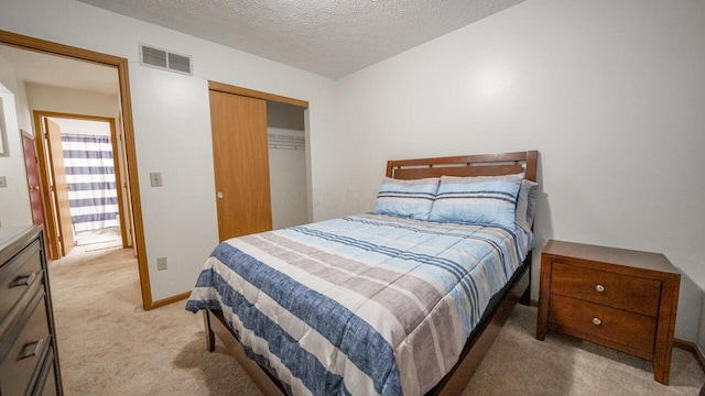 bedroom featuring light colored carpet, a textured ceiling, and a closet