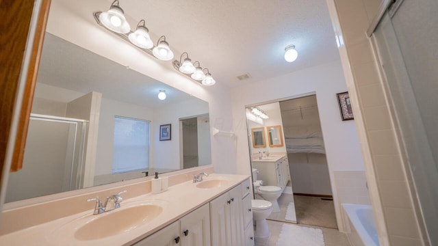 full bathroom with tile patterned flooring, vanity, separate shower and tub, toilet, and a textured ceiling