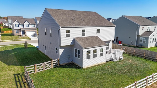 back of property featuring a wooden deck, a yard, and a garage