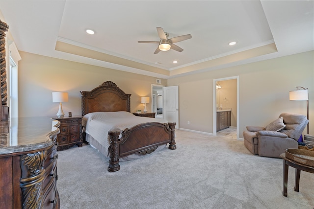 bedroom featuring ceiling fan, a tray ceiling, and ensuite bathroom