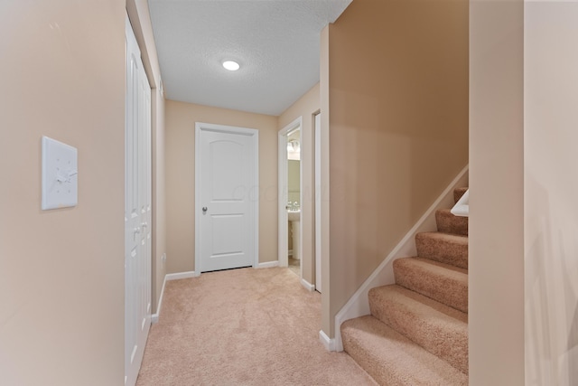 hall with a textured ceiling and light carpet