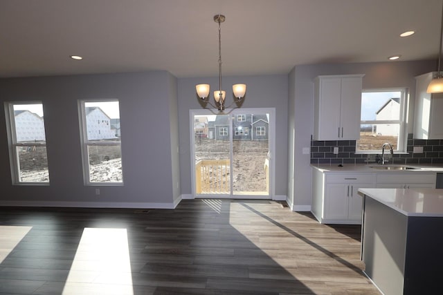 kitchen with light countertops, tasteful backsplash, a sink, and white cabinets