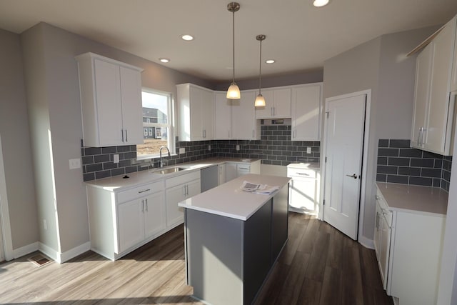 kitchen with dark wood-style flooring, a sink, a center island, baseboards, and decorative backsplash