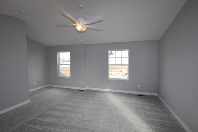 carpeted spare room featuring lofted ceiling, visible vents, a ceiling fan, and baseboards