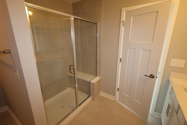 full bath with baseboards, a stall shower, vanity, and tile patterned floors