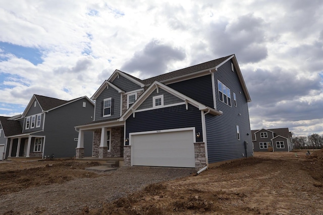 craftsman-style home featuring dirt driveway, stone siding, and a garage