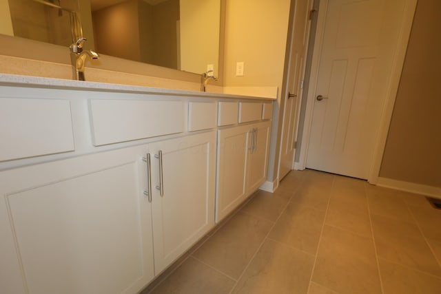 bathroom featuring tile patterned flooring, a sink, baseboards, and double vanity